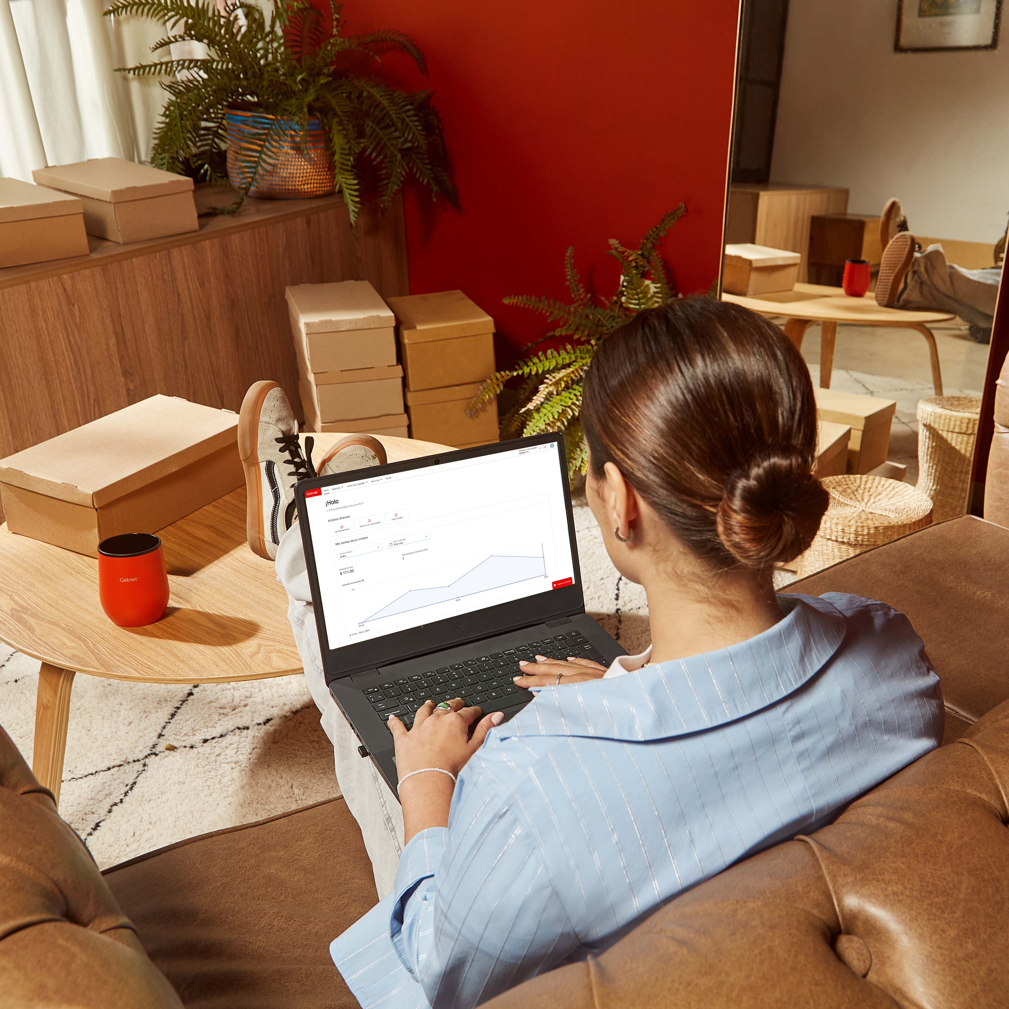 Persona sentada en un sofá usando una computadora portátil en una habitación.